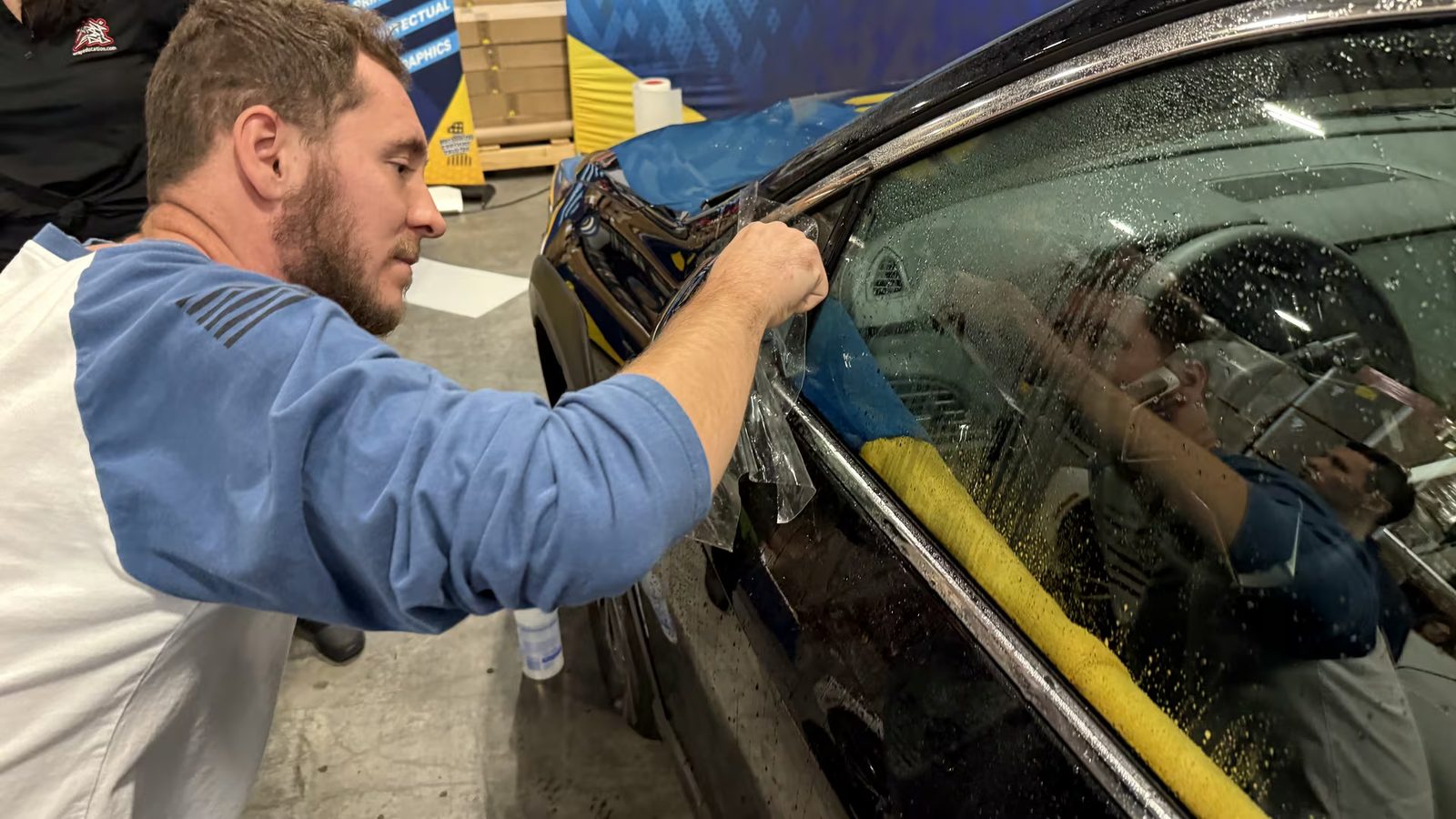 Detailer prepping a black vehicle with tape before polishing