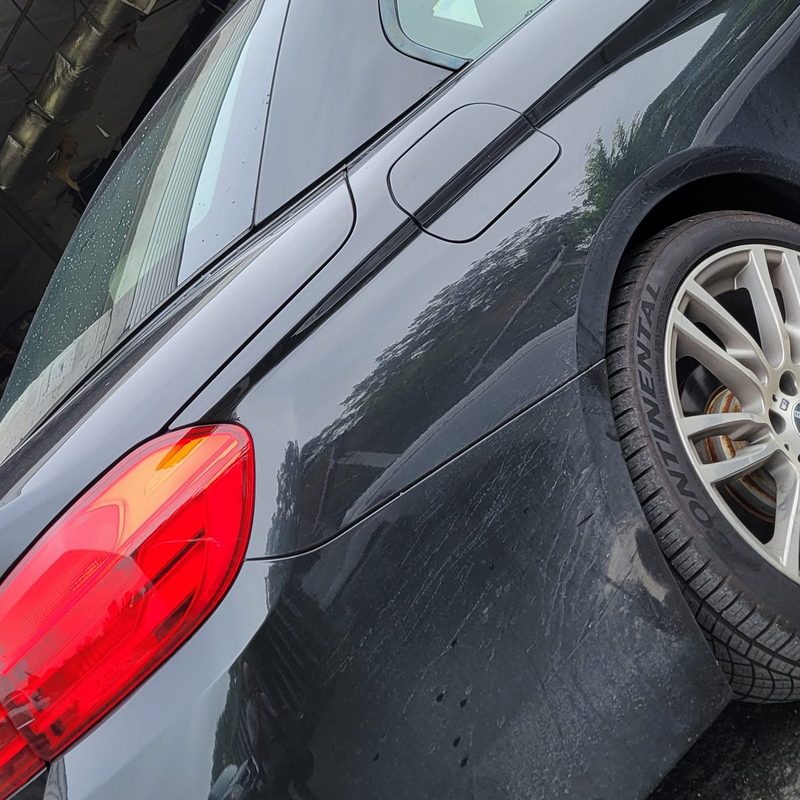 Dull, swirled black paint on a fender before machine polishing